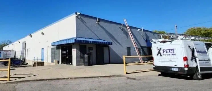 An Xpert Roofing van parked at a commercial building